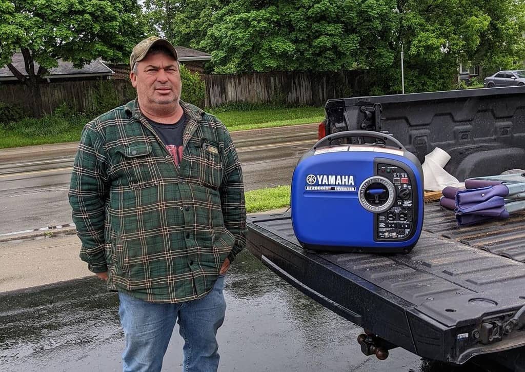 a man standing next to a blue portable generator