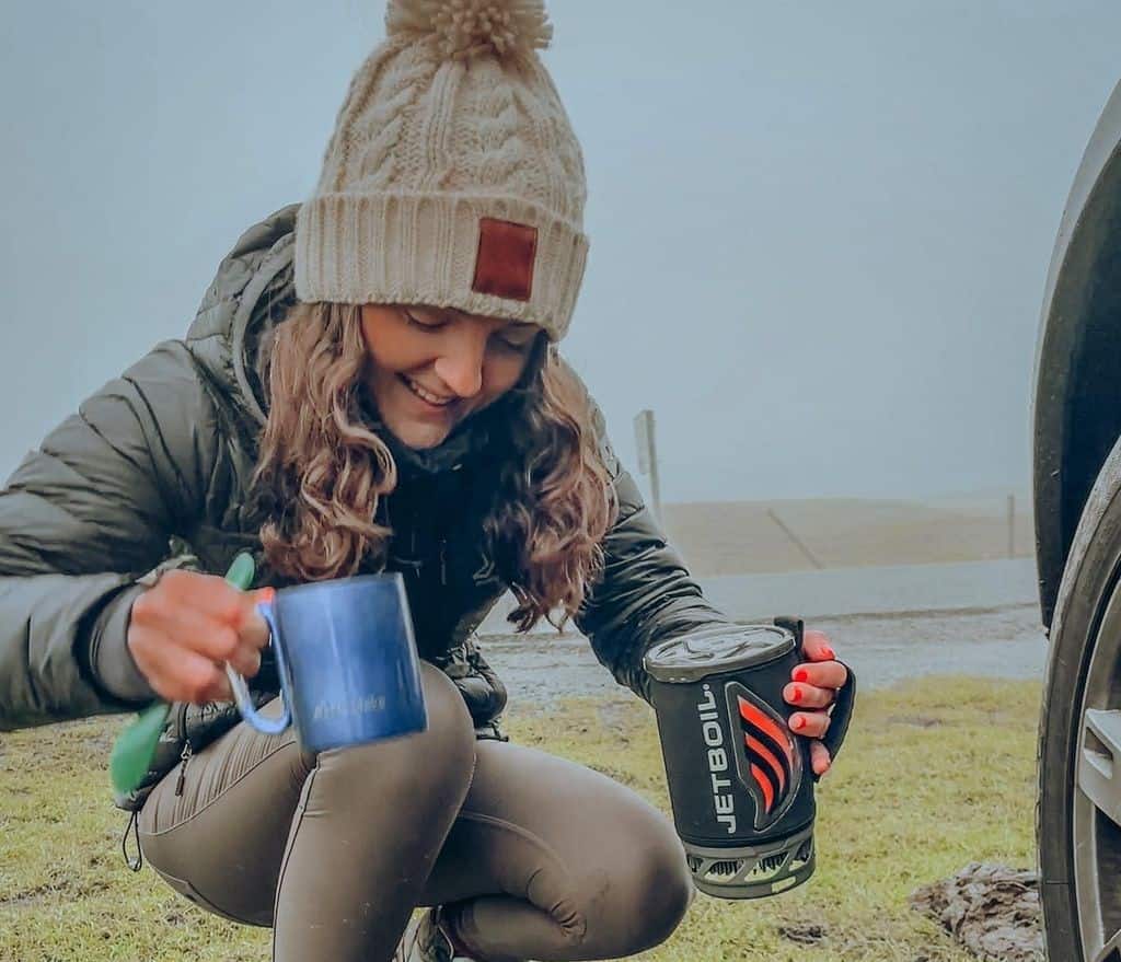 A girl pours tea from a jetboil burner