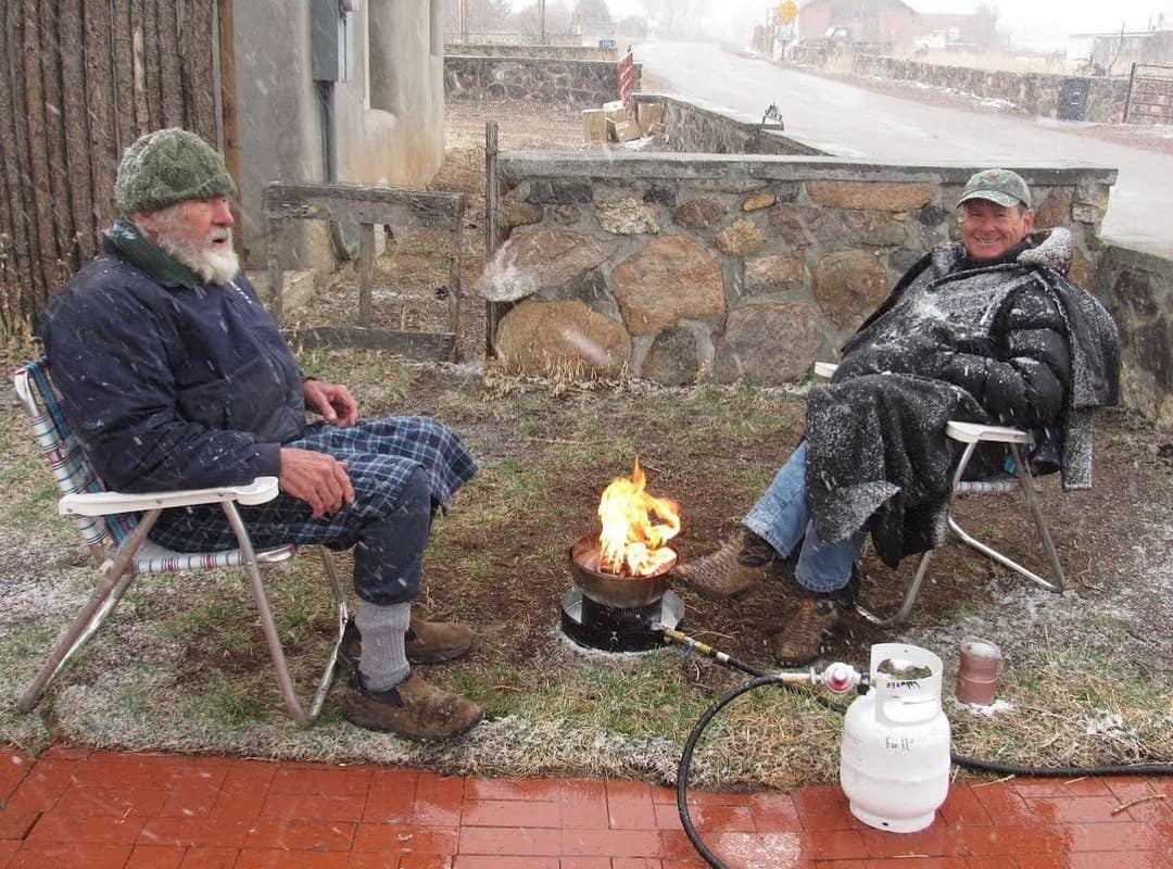 two hikers warming themselves by the gas fire