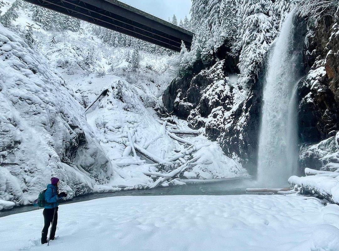hiker looking at a winter waterfall